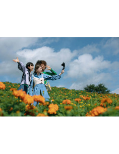 Tres personas en un campo de flores naranjas, sonriendo y t, capturado con Canon PowerShot V1 – Cámara compacta 4K para vlogg