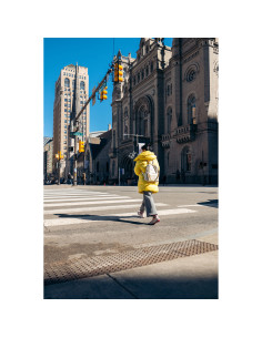 Une personne en manteau jaune traverse une rue devant un bâtiment, capture au Tamron 16-30mm f/2.8 Di III VXD G2 pour Nikon Z Une personne en manteau jaune traverse une rue devant un bâtiment, capture au Tamron 16-30mm f/2.8 Di III VXD G2 pour Nikon Z