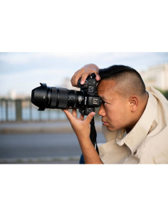 A person capturing a photo by a waterfront, casually styled, focused on, captured with Nikon NIKKOR Z 24-70mm f/2.8 S II Lens A person capturing a photo by a waterfront, casually styled, focused on, captured with Nikon NIKKOR Z 24-70mm f/2.8 S II Lens