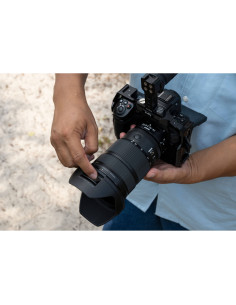 A person adjusting a camera outdoors, holding it with care, surrounded, captured with Nikon NIKKOR Z 24-70mm f/2.8 S II Lens A person adjusting a camera outdoors, holding it with care, surrounded, captured with Nikon NIKKOR Z 24-70mm f/2.8 S II Lens
