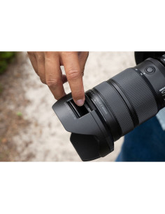 A person adjusting a camera lens outdoors, surrounded by greenery and s, captured with Nikon NIKKOR Z 24-70mm f/2.8 S II Lens A person adjusting a camera lens outdoors, surrounded by greenery and s, captured with Nikon NIKKOR Z 24-70mm f/2.8 S II Lens