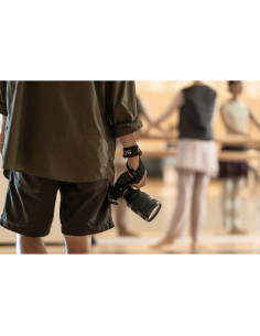 Un fotógrafo sostiene una cámara mientras observa a las bailarinas en un estudio lumino, capturado con Sony FE 28-70mm f/2 GM Un fotógrafo sostiene una cámara mientras observa a las bailarinas en un estudio lumino, capturado con Sony FE 28-70mm f/2 GM