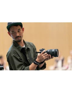 Hombre sosteniendo una cámara con enfoque en su rostro, fondo desenfocado de un evento, capturado con Sony FE 28-70mm f/2 GM Hombre sosteniendo una cámara con enfoque en su rostro, fondo desenfocado de un evento, capturado con Sony FE 28-70mm f/2 GM