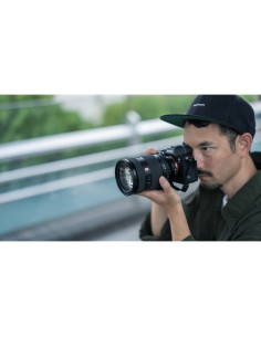 Un fotógrafo enfocado en su trabajo, luz natural y entorno urbano difuminado, capturado con Sony FE 28-70mm f/2 GM Un fotógrafo enfocado en su trabajo, luz natural y entorno urbano difuminado, capturado con Sony FE 28-70mm f/2 GM