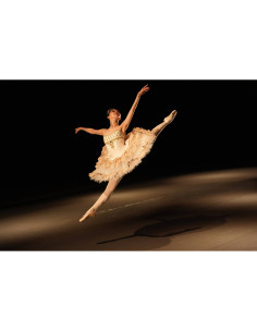 Bailarina en el aire con vestido claro, escenario oscuro y foco de luz sobre ella, capturado con Sony FE 28-70mm f/2 GM Bailarina en el aire con vestido claro, escenario oscuro y foco de luz sobre ella, capturado con Sony FE 28-70mm f/2 GM