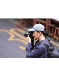A man dressed casually holding a camera, focused on capturing a scene outdoors, captured with Sony FE 16mm f/1.8 G A man dressed casually holding a camera, focused on capturing a scene outdoors, captured with Sony FE 16mm f/1.8 G