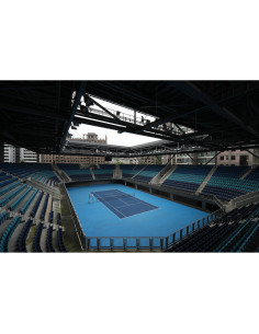 An empty tennis stadium with blue courts under a dark metal framework and urban backdrop, captured with Sony FE 16mm f/1.8 G An empty tennis stadium with blue courts under a dark metal framework and urban backdrop, captured with Sony FE 16mm f/1.8 G
