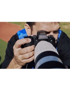 Photographe capturant une scène en extérieur, concentré sur sa prise de vue, capture au Sony Alpha 1 II
