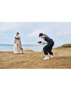 Photographe capturant une modèle en robe sur une falaise face à la mer, capture au Sony Alpha 1 II