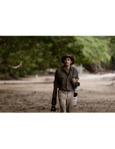 Photographe marchant dans un environnement naturel, portant un chapeau et tenant un appareil phot, capture au Sony Alpha 1 II