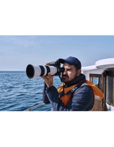 Photographe en mer avec appareil photo, portant une veste de sauvetage et un chapeau, capture au Sony Alpha 1 II