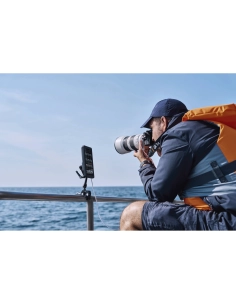 Un homme photographie la mer depuis un bateau avec un smartphone installé à côté de lui, capture au Sony Alpha 1 II