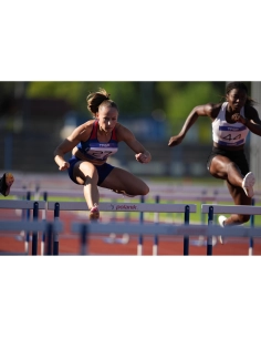 Deux athlètes en plein saut au-dessus de haies sur une piste d'athlétisme ensoleillée, capture au Sony Alpha 1 II