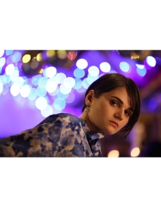 Joven con blusa azul en ambiente festivo con luces de fondo desenfocadas, capturado con Canon RF 135mm f/1.8 L IS USM