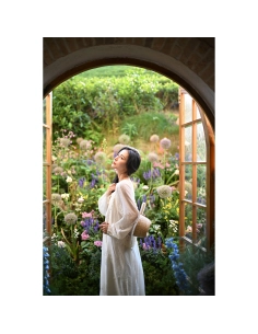 Femme en robe blanche devant des fenêtres avec jardin fleuri, capture au Nikon Z 50mm f/1.4 Femme en robe blanche devant des fenêtres avec jardin fleuri, capture au Nikon Z 50mm f/1.4
