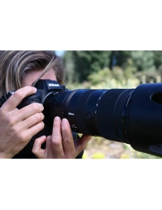 A person photographing nature with a camera, lush greenery in the background, captured with Nikon Z 70-200mm f/2.8 VR S II A person photographing nature with a camera, lush greenery in the background, captured with Nikon Z 70-200mm f/2.8 VR S II
