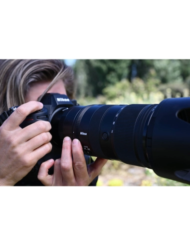 A person photographing nature with a camera, lush greenery in the background, captured with Nikon Z 70-200mm f/2.8 VR S II