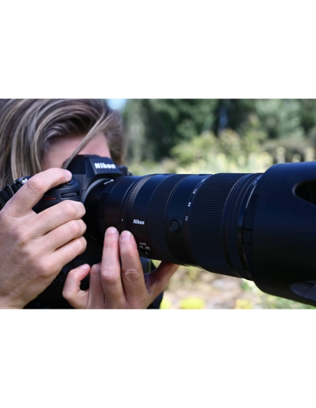 Una persona enfoca con una cámara Nikon en un entorno natural