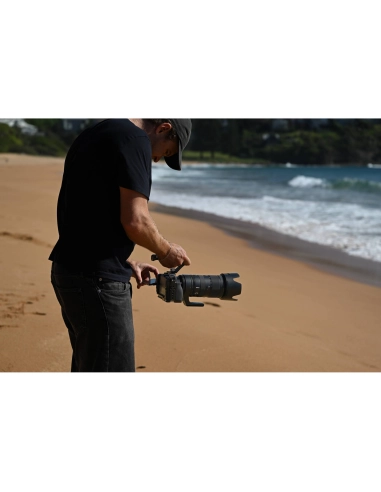 A man adjusting his camera lens on a beach, captured with Nikon Z 70-200mm f/2.8 VR S II