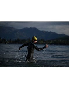 A swimmer in a wetsuit splashes in the water with mountains in the background, captured with Nikon Z 70-200mm f/2.8 VR S II A swimmer in a wetsuit splashes in the water with mountains in the background, captured with Nikon Z 70-200mm f/2.8 VR S II