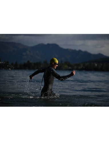 A swimmer in a wetsuit splashes in the water with mountains in the background, captured with Nikon Z 70-200mm f/2.8 VR S II