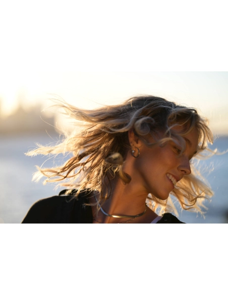 Mujer con cabello al viento sonriendo al atardecer en la playa, capturado con Nikon NIKKOR Z 70-200mm f/2.8 VR S II