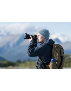 Un hombre con mochila y gorro gris fotografía un paisaje montañoso, capturado con Sony a7R VI Un hombre con mochila y gorro gris fotografía un paisaje montañoso, capturado con Sony a7R VI