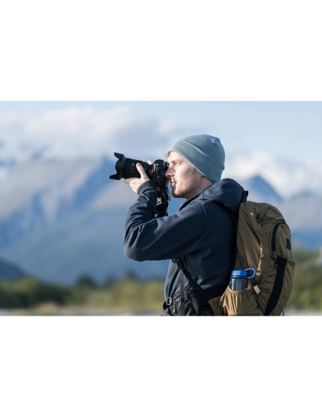 Un hombre con mochila y gorro gris fotografía un paisaje montañoso, capturado con Sony a7R VI