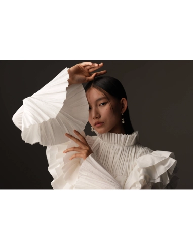 Modelo con blusa blanca de volantes en un fondo oscuro, mostrando poses elegantes y expresivas, capturado con Sony a7R VI