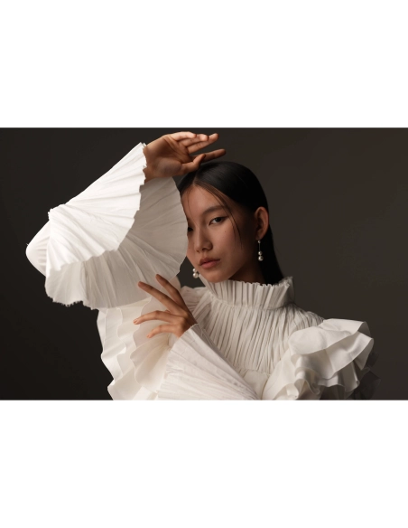 Modelo con blusa blanca de volantes en un fondo oscuro, mostrando poses elegantes y expresivas, capturado con Sony a7R VI