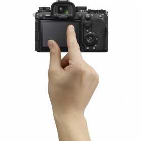 A hand gently touches the back of a camera, focusing on its screen in a bright setting, captured with Sony A9 III A hand gently touches the back of a camera, focusing on its screen in a bright setting, captured with Sony A9 III