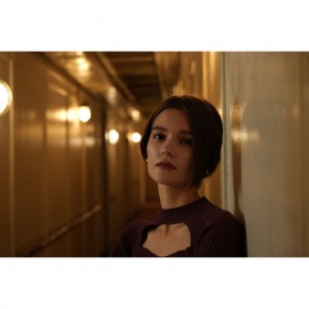 Femme appuyée contre un mur dans un couloir éclairé, ambiance tamisée, capture au Sony FE 20-70mm f/4 G