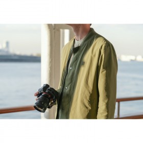 Une personne tenant un appareil photo sur un quai au bord de l’eau, capture au Sony FE 20-70mm f/4 G