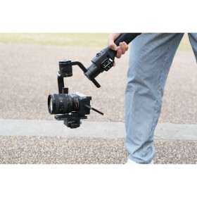 Un homme tient un stabilisateur avec un appareil photo au milieu d'un espace extérieur, capture au Sony FE 20-70mm f/4 G