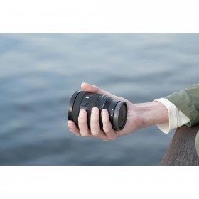 Un homme tient un objectif Sony au bord de l'eau, ambiance calme et naturelle