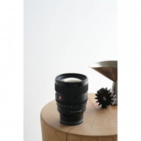 Un ambiente minimalista con un objeto sobre una mesa de madera, capturado con Sony FE 85mm f/1.4 GM II