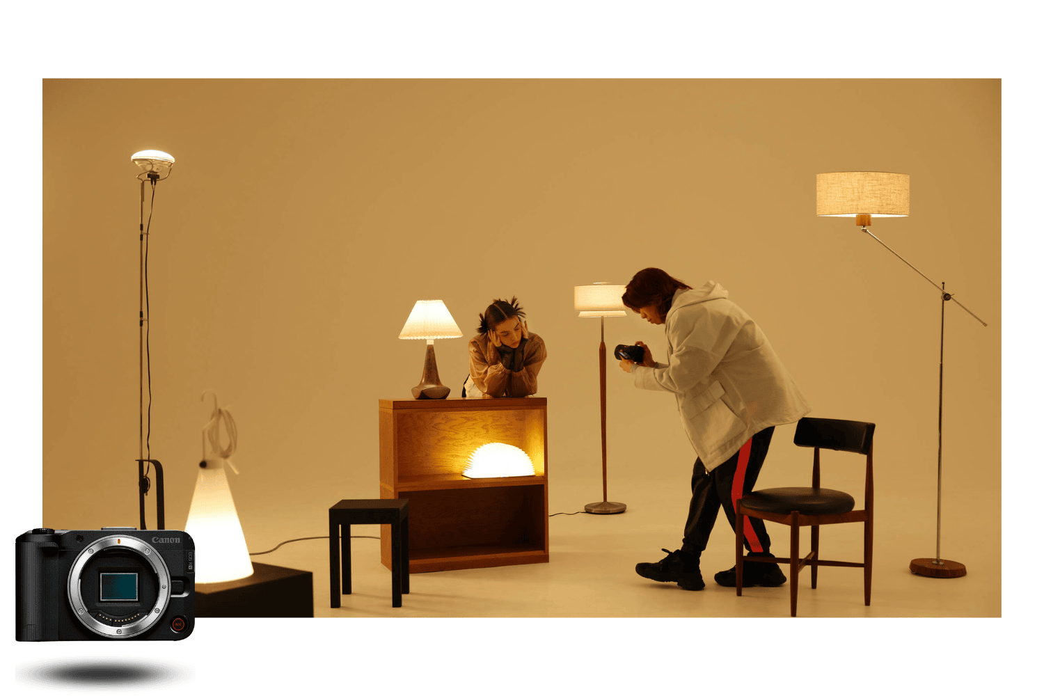 Appareil photo hybride Canon EOS R50 V en séance photo studio, créateur cadrant un modèle parmi des lampes